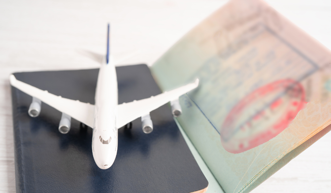 Toy airplane placed on a passport with an entry stamp, symbolising international travel and migration.
